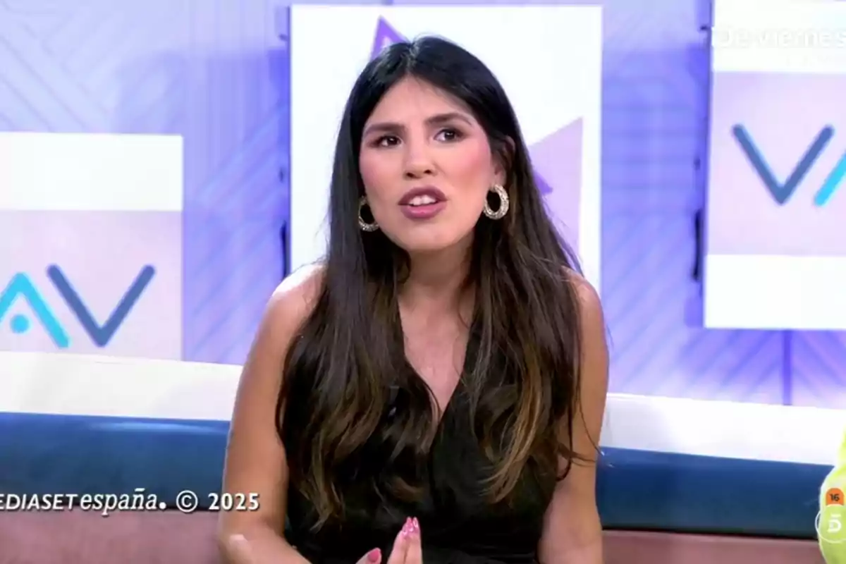 Isa Pantoja amb cabell llarg i fosc està asseguda en un plató de televisió parlant, porta un vestit negre i arracades grans, el fons té un disseny geomètric i logotips. Captura de 'Vamos a ver'.