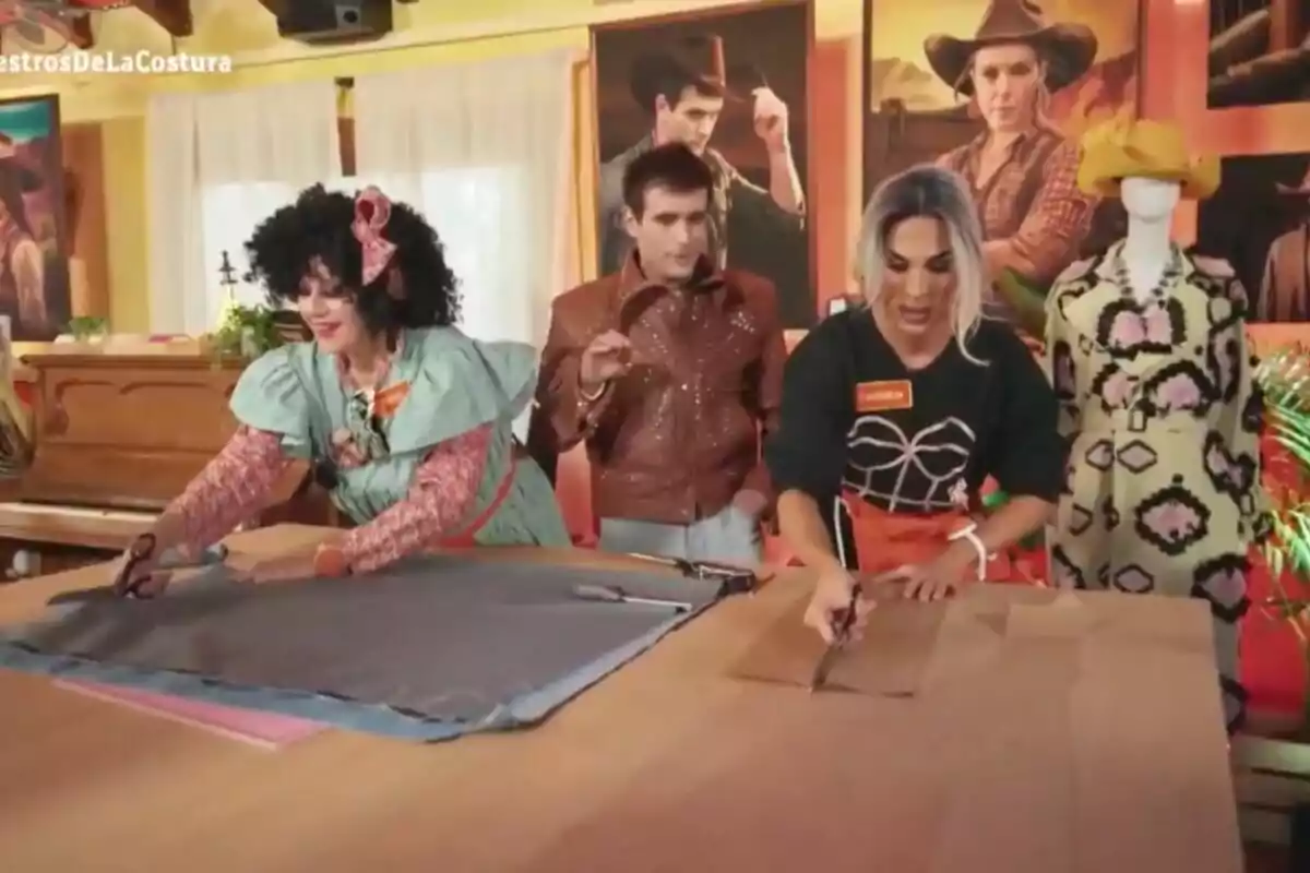 La Terre, Carmen Farala y Palomo Spain está en una sala colorida trabajando en un proyecto de costura, con telas extendidas sobre una mesa y tijeras en mano, mientras un maniquí vestido se encuentra al fondo. La Terre, Carmen Farala y Palomo Spain está en una sala colorida trabajando en un proyecto de costura, con telas extendidas sobre una mesa y tijeras en mano, mientras un maniquí vestido se encuentra al fondo.