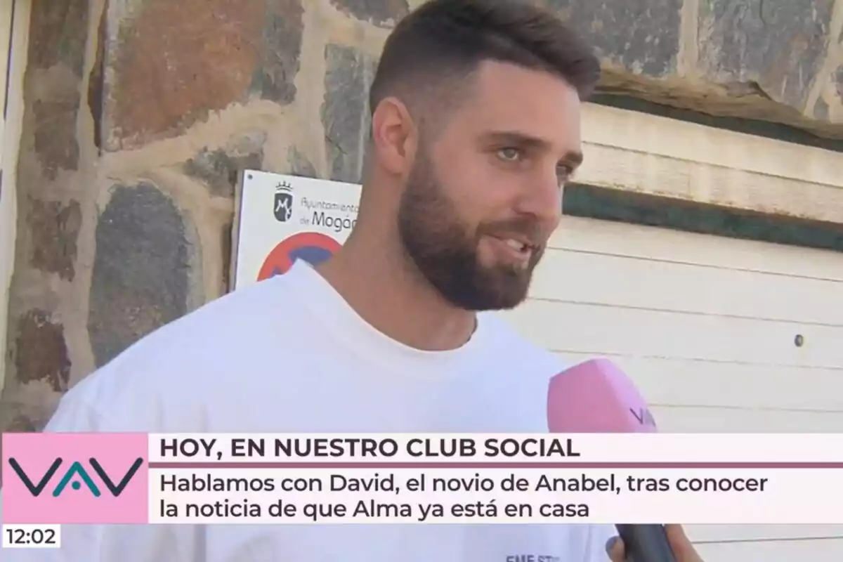 David Rodríguez con barba es entrevistado por un canal de televisión llamado 'Vamos a ver' frente a un edificio de piedra.