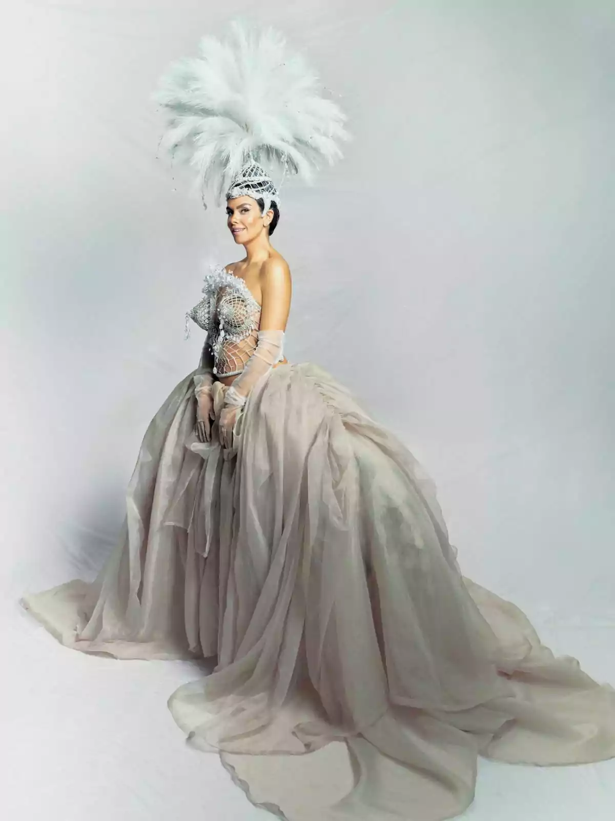 Cristina Pedroche con un vestido elegante y un tocado de plumas blancas posando en un fondo claro. Cristina Pedroche con un vestido elegante y un tocado de plumas blancas posando en un fondo claro.