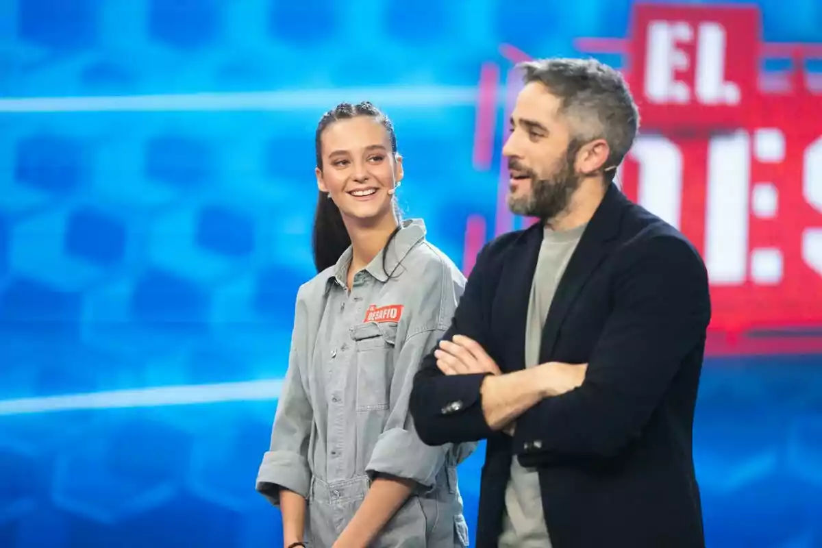 Victoria Federica y Roberto Leal en un set de televisión con un fondo azul y un letrero rojo que dice Victoria Federica y Roberto Leal en un set de televisión con un fondo azul y un letrero rojo que dice