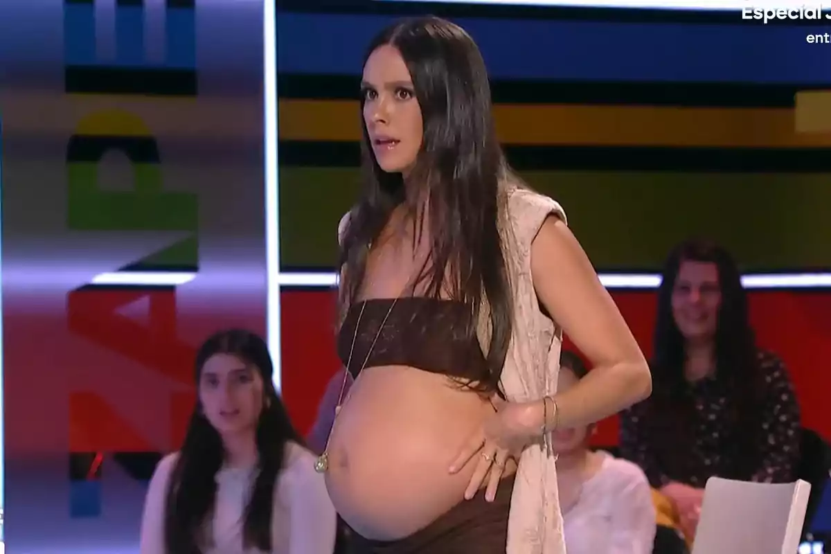 Cristina Pedroche embarassada amb vestit marró i cabell llarg està dreta en un escenari amb persones assegudes al fons. Captura de 'Zapeando' Cristina Pedroche embarassada amb vestit marró i cabell llarg està dreta en un escenari amb persones assegudes al fons. Captura de 'Zapeando'